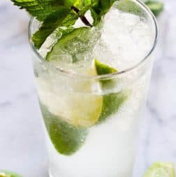 Classic mojito garnished with lime wedges and mint leaves.