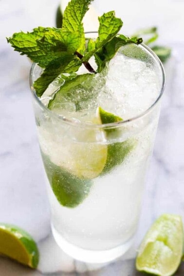 Classic mojito garnished with lime wedges and mint leaves.