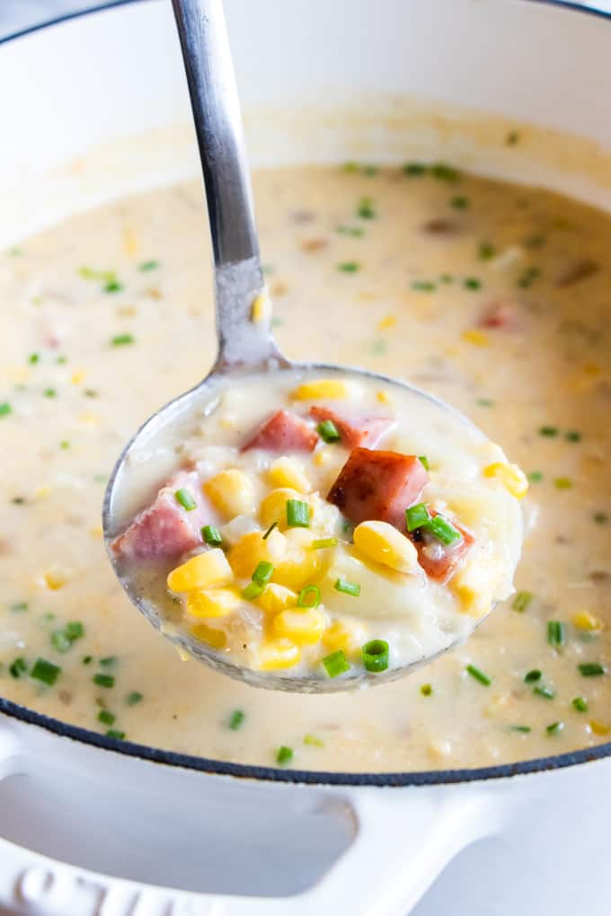 A ladle spooning out homemade corn chowder.