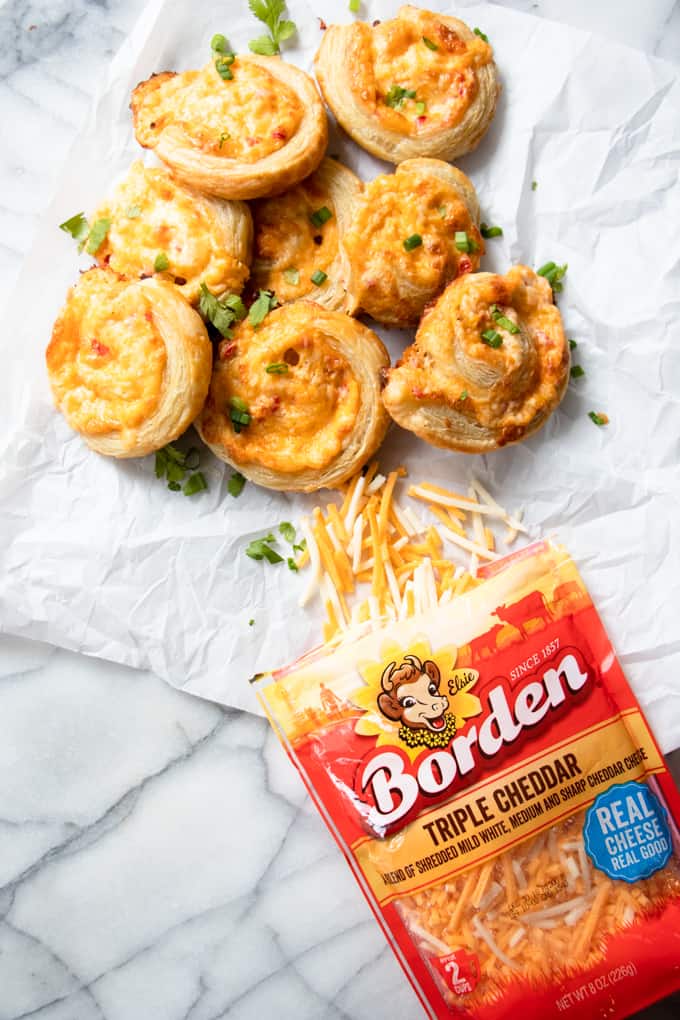 A bag of Borden Shredded cheese spilling out next to homemade pimento cheese pinwheels.