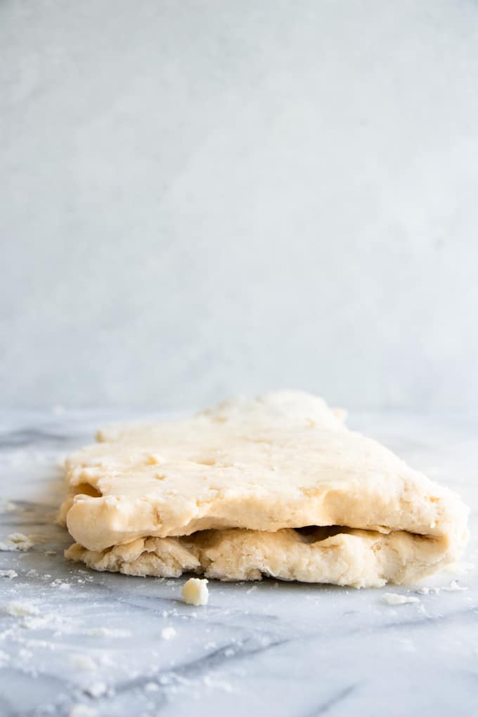 Homemade biscuit dough being folded over to create layers for baking.
