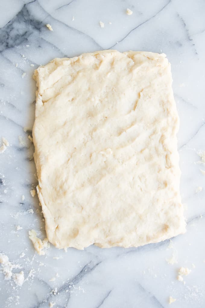 Homemade biscuit dough pressed out into a rectangle, ready to be cut into biscuits.
