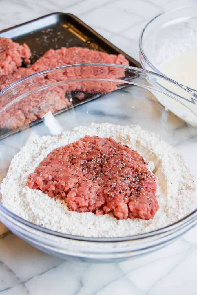 How to Make chicken Fried Steak: placing a seasoned cube steak into flour mixture.