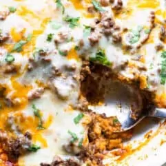 Close up of tamale pie showing the cornbread crust, ground beef topping and melted cheese on top.