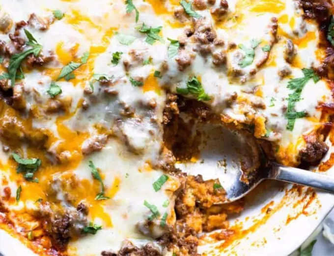 Close up of tamale pie showing the cornbread crust, ground beef topping and melted cheese on top.