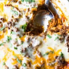 Close up of tamale pie showing the cornbread crust, ground beef topping and melted cheese on top.