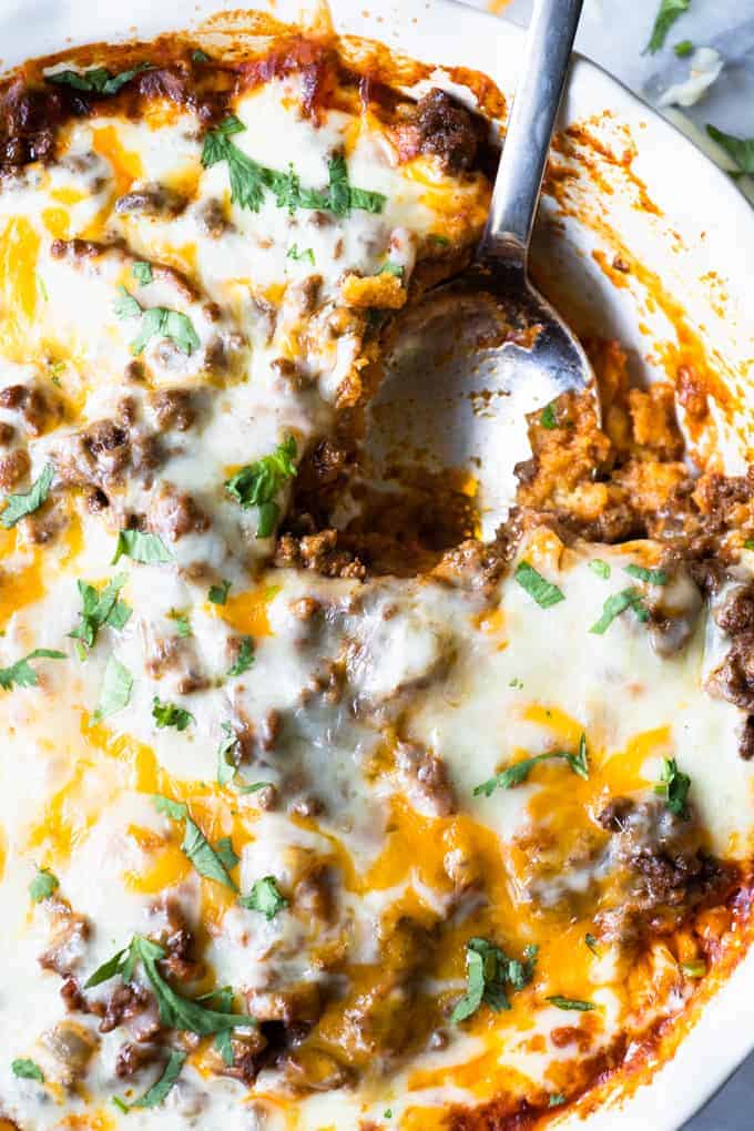 Close up of tamale pie showing the cornbread crust, ground beef topping and melted cheese on top.