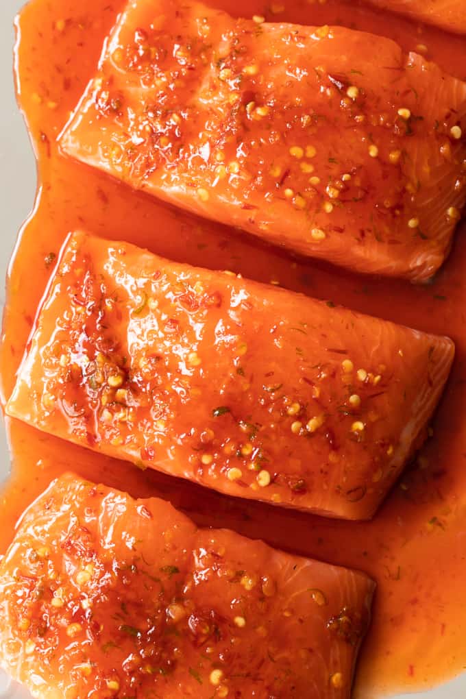 Saumon cru sur une plaque à pâtisserie et badigeonné de sauce chili-citron vert prêt à cuire. 