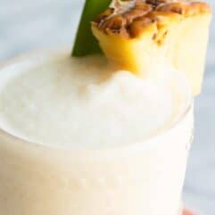 Up close of cold and frosty Pina coladas with a wedge of pineapple.
