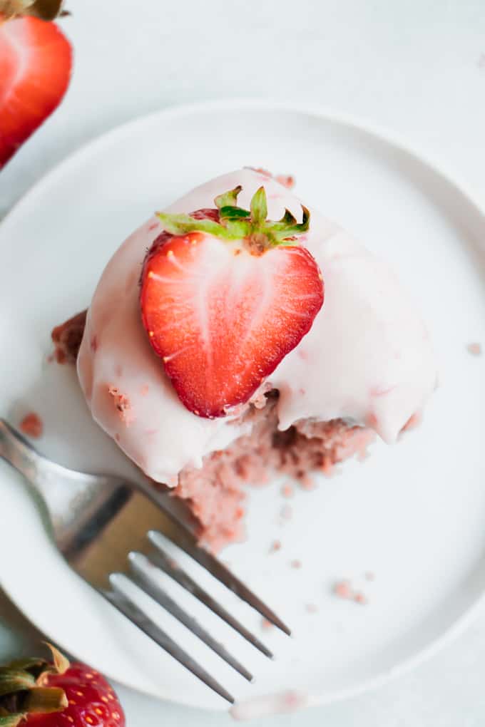 Overhead view of homemade strawberry cake with a sliced strawberry on top.