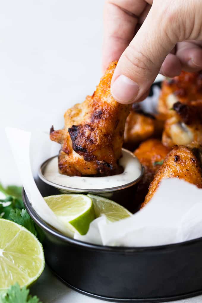 Chile Lime Chicken Wings dipping into a small cup of ranch.