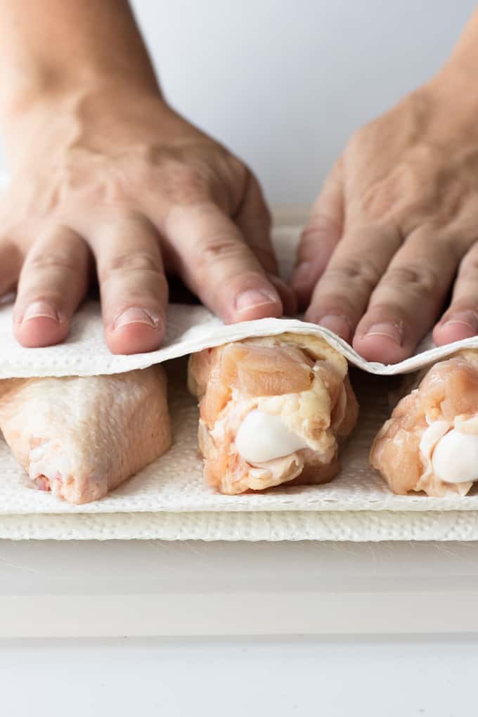 Chicken wings being pat dry with paper towels ready to make baked Chile lime chicken wings.