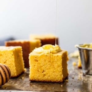Slices of cornbread being served with butter and a drizzle of honey.