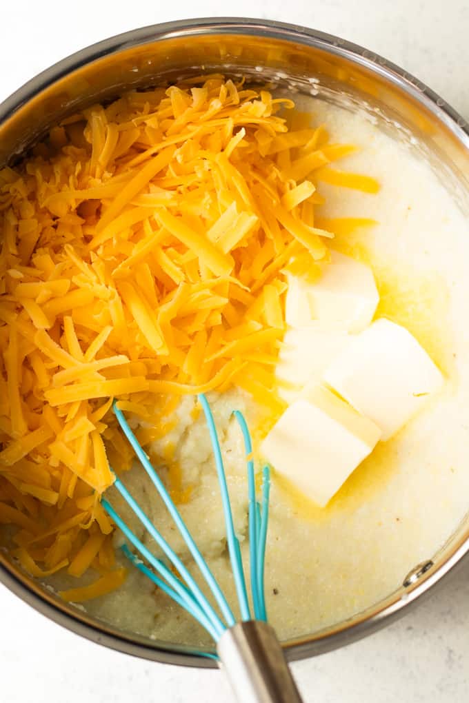 Making grits in a saucepan, adding shredded cheese and butter to mix in.