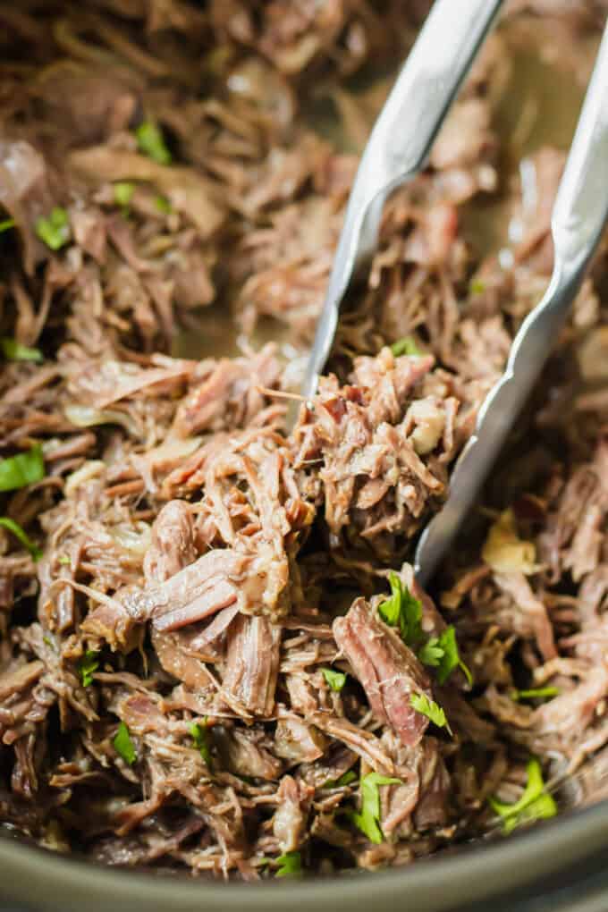 Rindfleisch-Barbacoa wird mit einer Zange serviert.