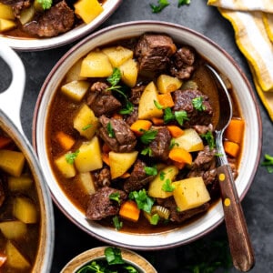 Bowl of beef stew topped with fresh herbs.