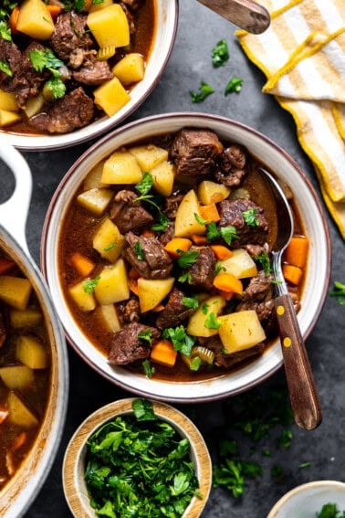 Bowl of beef stew topped with fresh herbs.