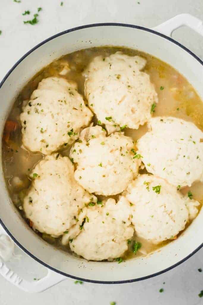 Large dutch oven filled with chicken stew topped with garlic herb dumplings.