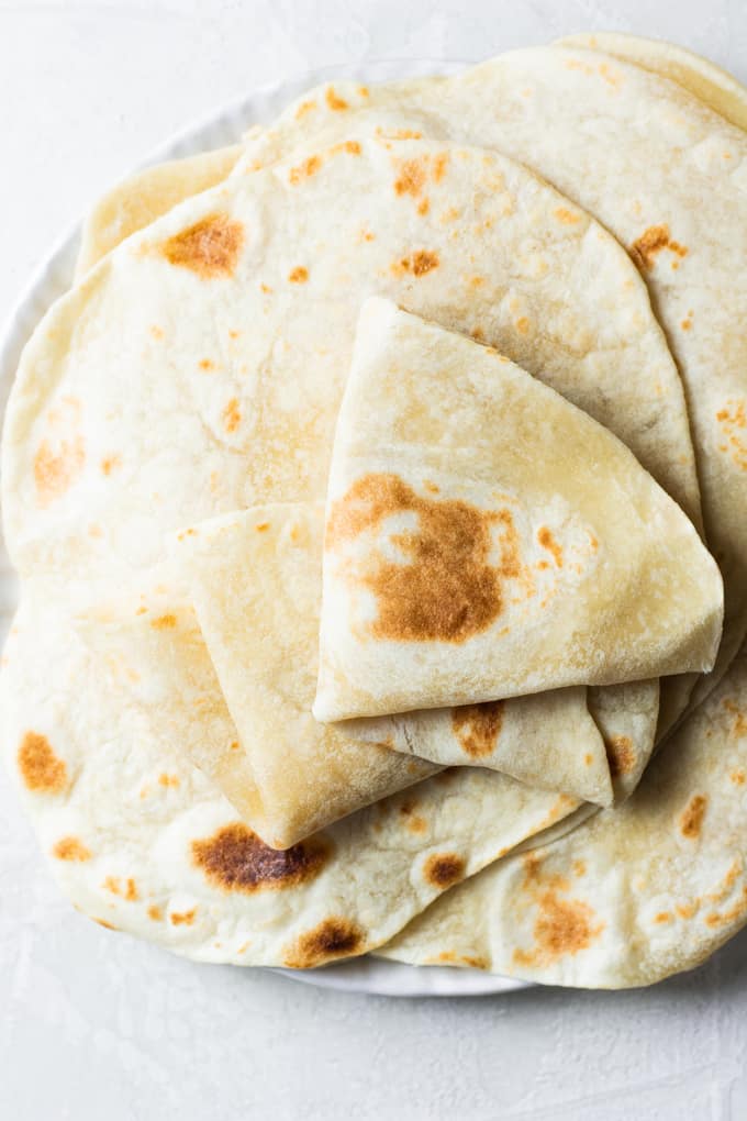 A plate filled with freshly made flour tortillas. 