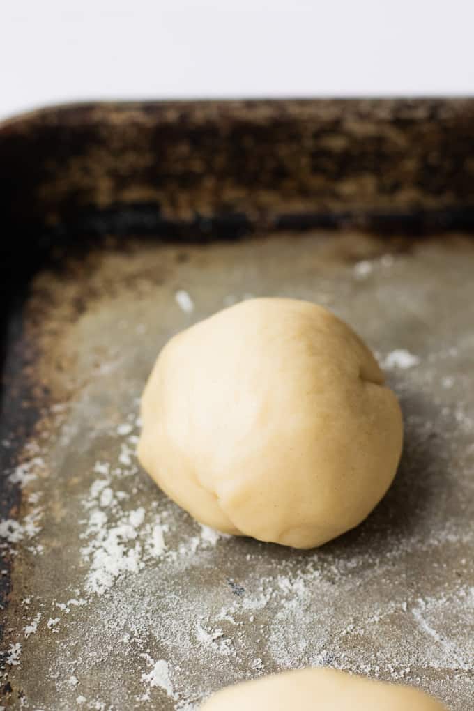 A ball of flour tortilla dough resting on a baking sheet.