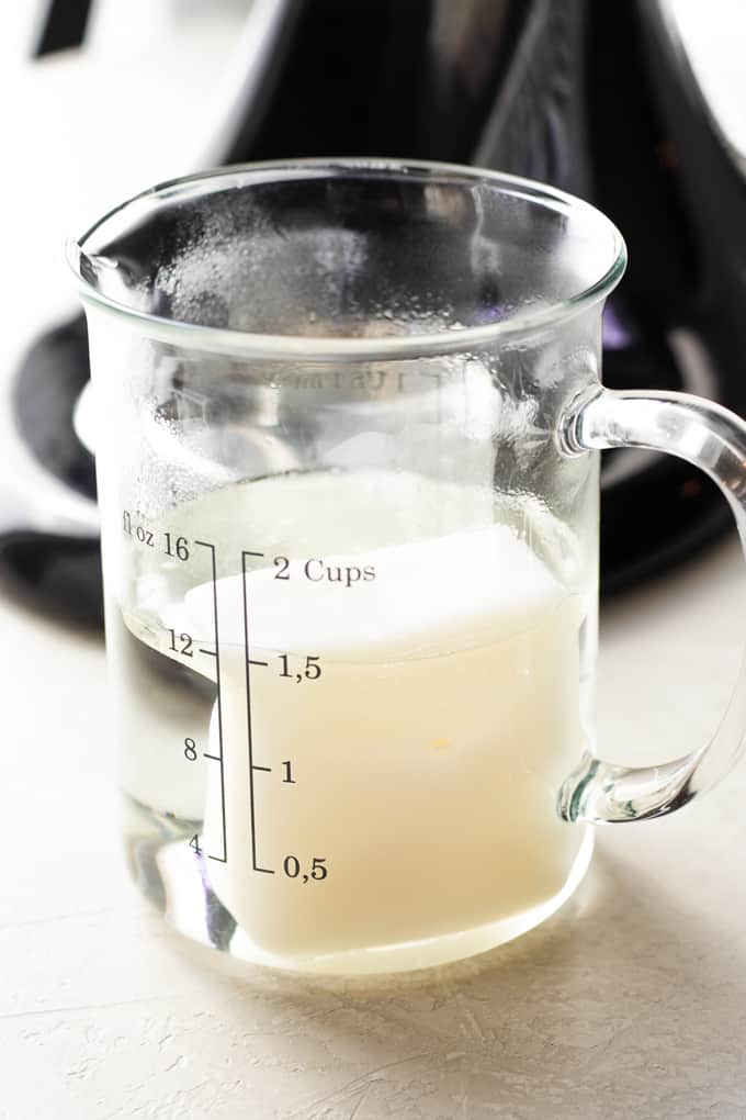 A measuring cup with warm water and a block of lard in it ready to melt and make homemade tortillas.
