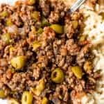 Homemade cuban picadillo served over white rice and served with a fork.