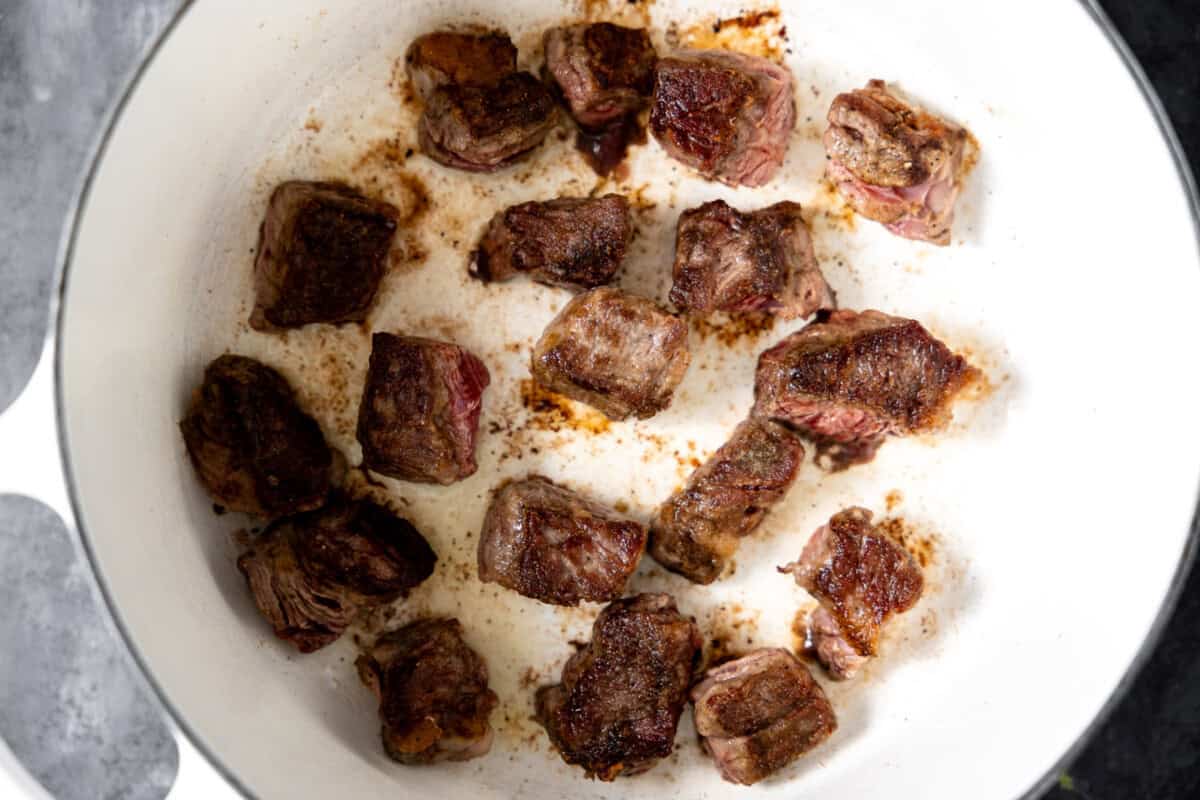 Seared chuck roast in a white dutch oven.