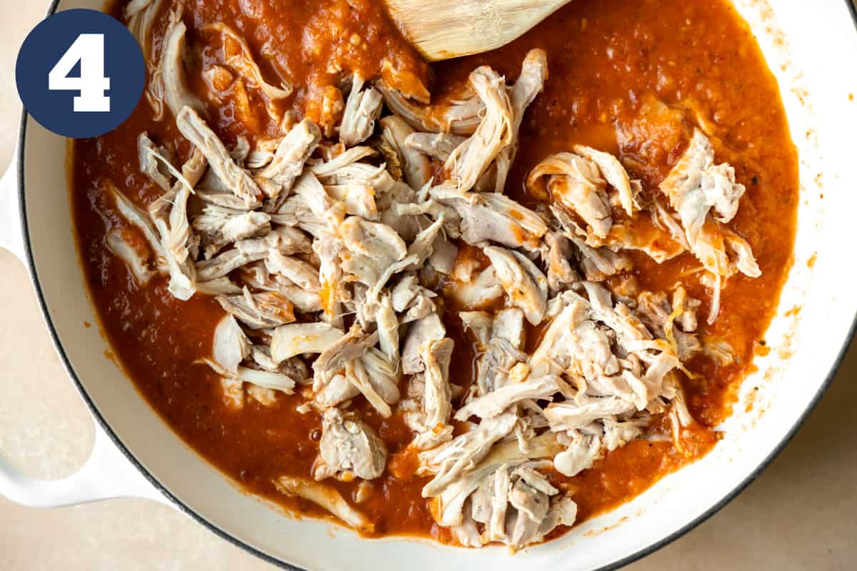 Shredded chicken added into a red chipotle sauce for simmering.