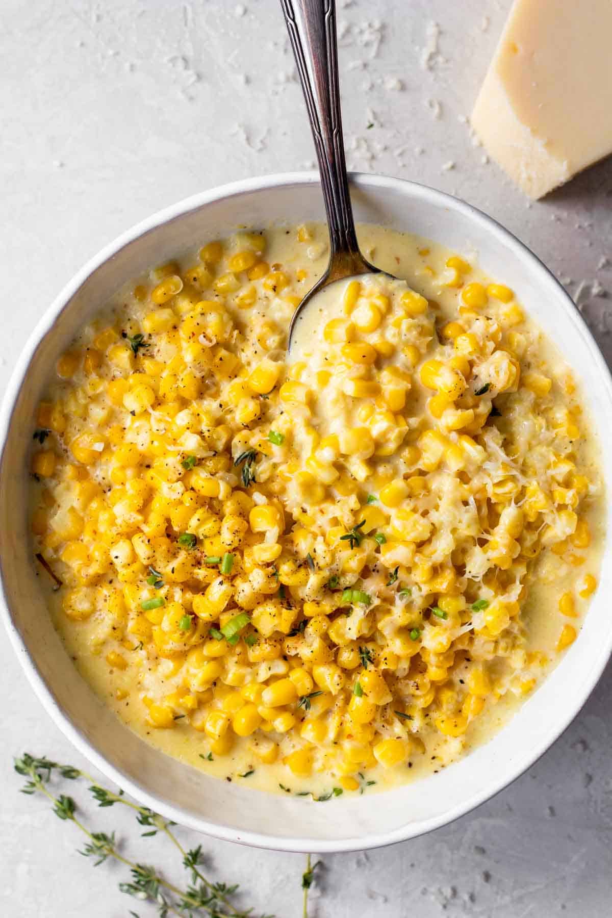 Bowl of creamed corn served with a spoon.