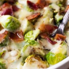 Baked Creamy Brussels sprouts in a baking dish with a spoon scooping up.