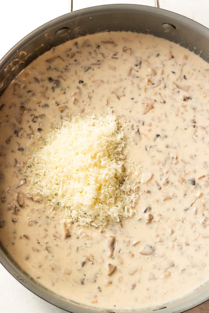 Creamy mushroom sauce with freshly grated parmesan on top ready to mix.