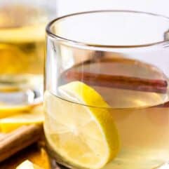 Hot Toddy with honey and Lemon in a glass mug garnished with a cinnamon stick.