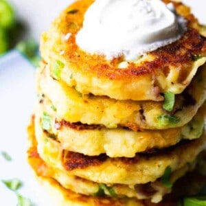 Loaded mashed potato cakes stacked and topped with sour cream.