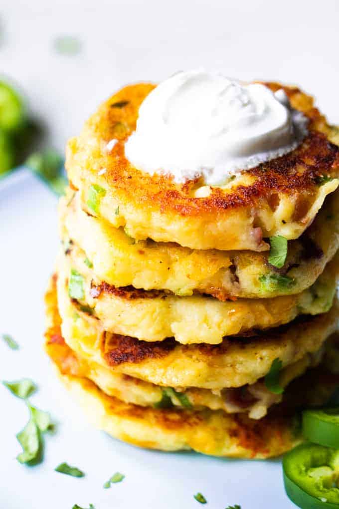 Loaded mashed potato cakes stacked and topped with sour cream. 
