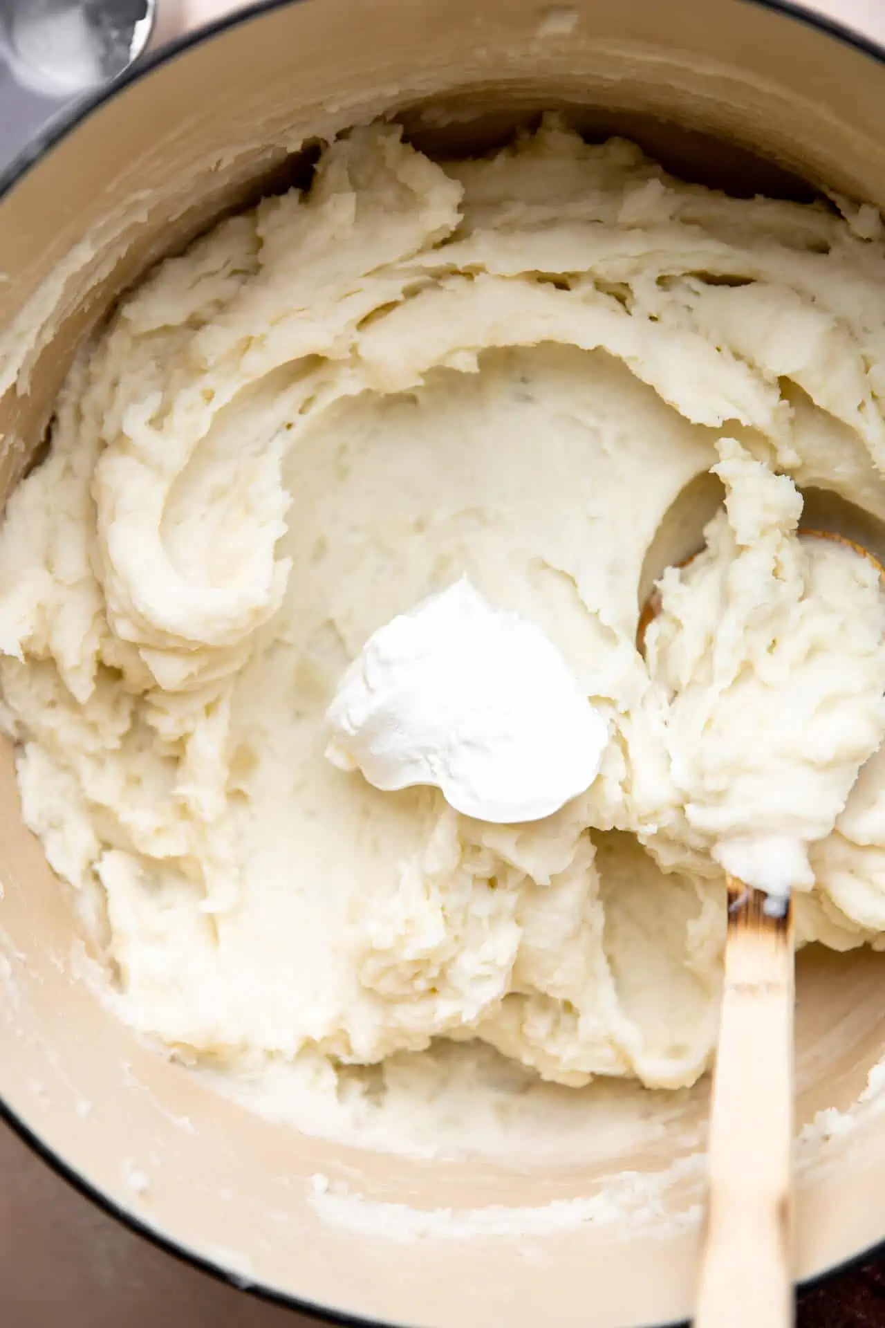 Pot filled with mashed potatoes and adding in sour cream.