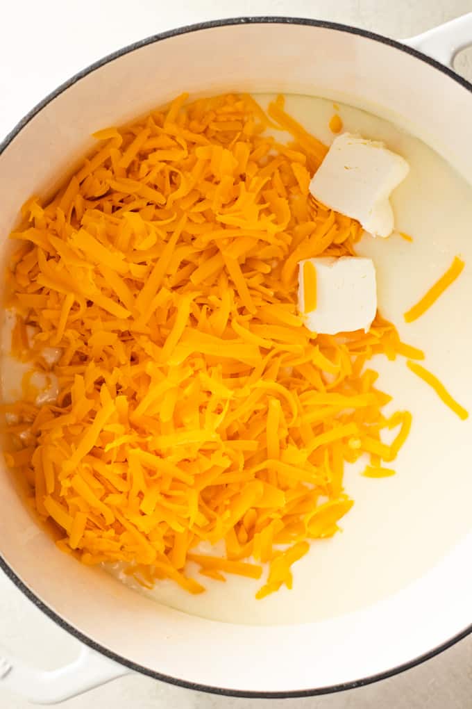Butter and shredded cheese added to a roux for making homemade cheese sauce for macaroni and cheese.