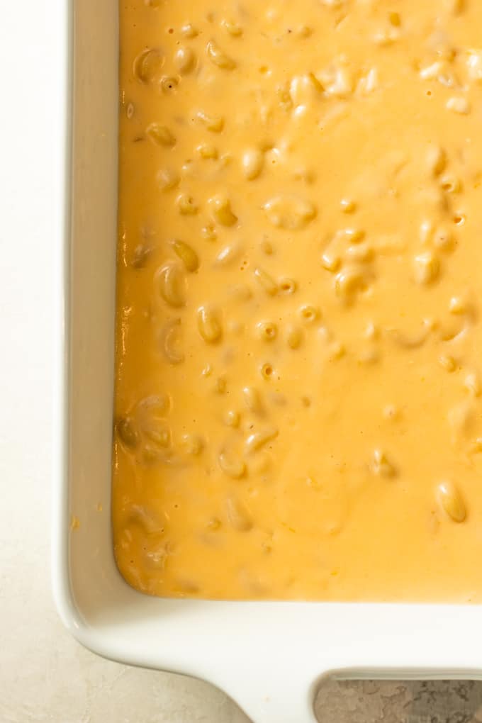 Macaroni and cheese added to a baking dish, showing the extra sauce consistency needed for baking macaroni and cheese.