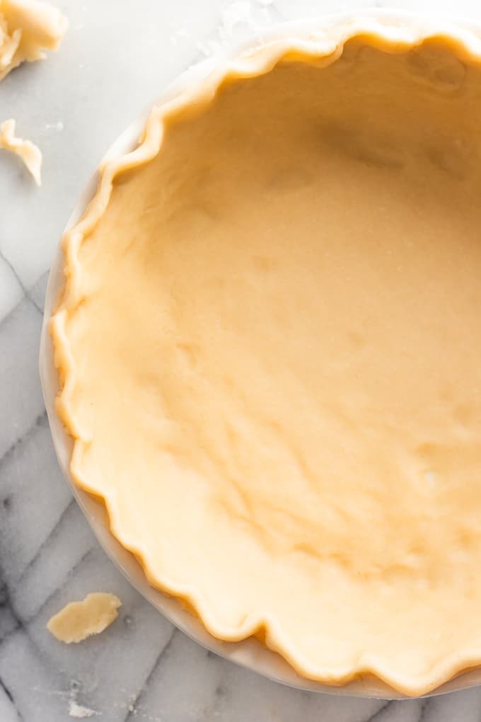 Pie crust in a glass pie dish fluted and ready to be filled.