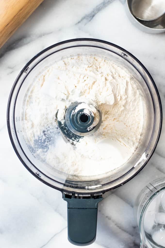 Food processor filled with dry ingredients to make butter pie crust.