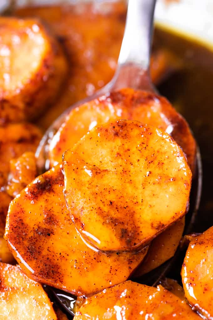 Spoon dishing up baked candied sweet potatoes. 
