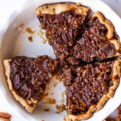 Pie dish with sliced pecan pie, a couple pieces have been removed.