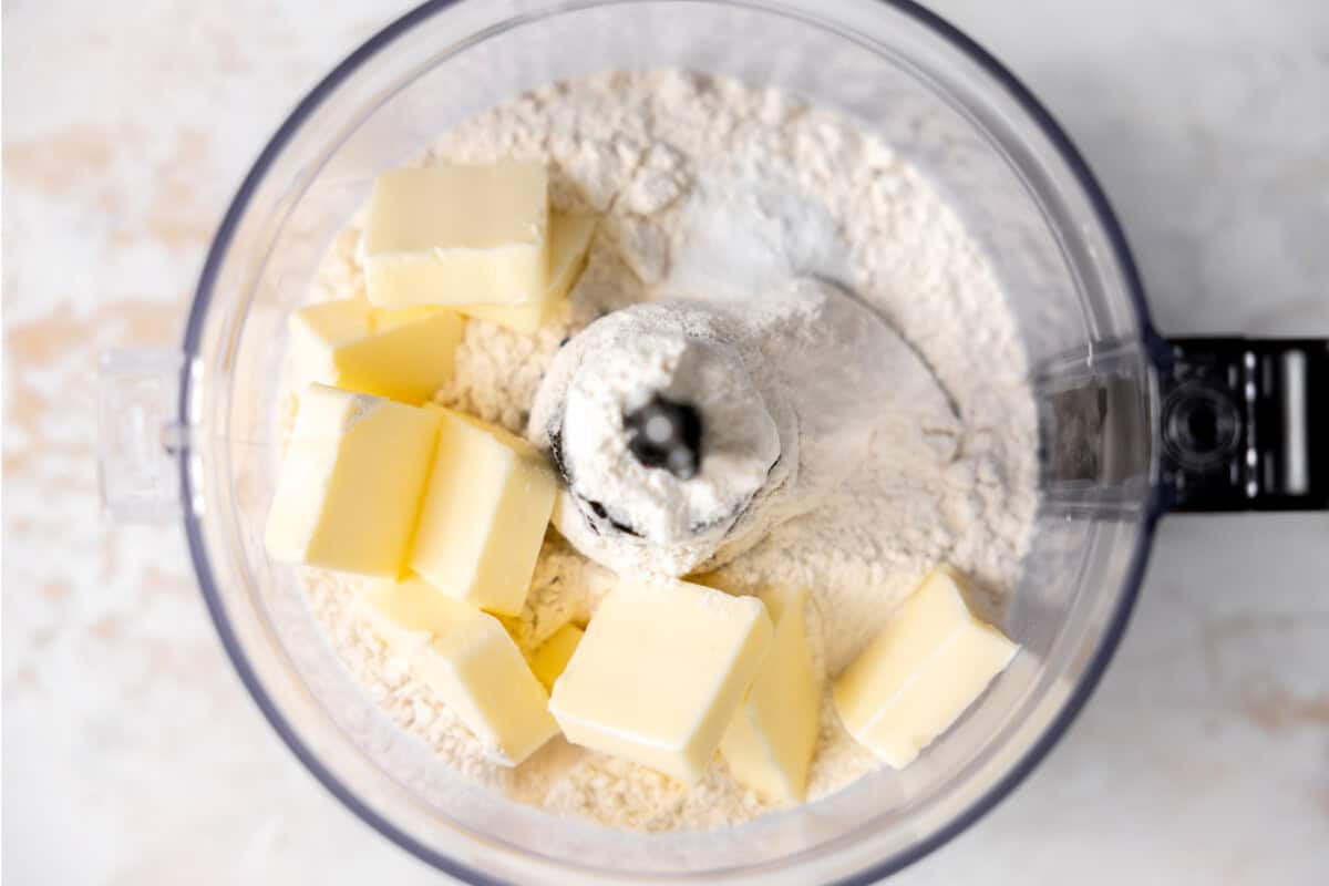 Flour, salt, and baking powder in a food processor with pieces of butter added to make a pie crust. 