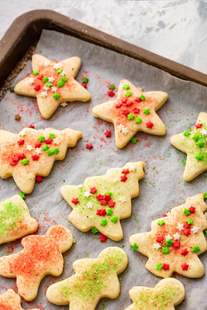 Cut out sugar cookies decorated with sprinkles, on a baking sheet.