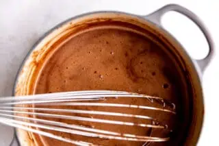 Smooth hot chocolate in a pot with a whisk.