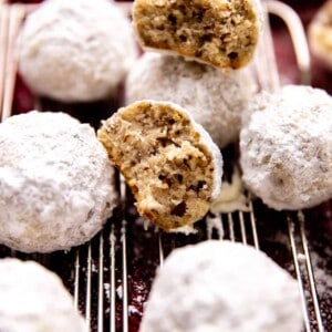 Mexican Wedding cookies on a wire rack with one split open to show pecans inside.