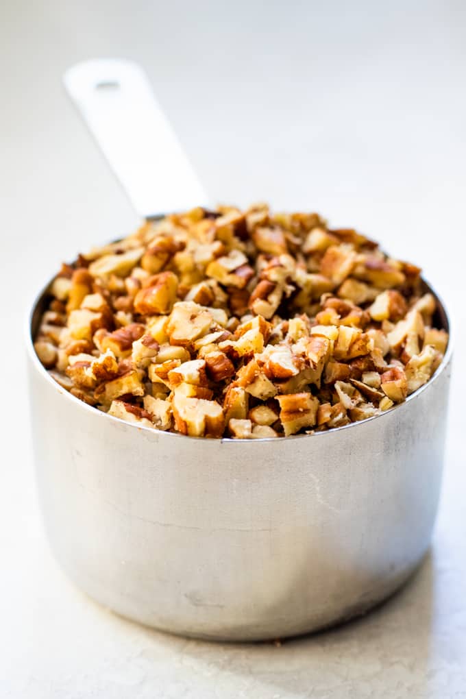 Measuring cup filled with finely chopped pecans.