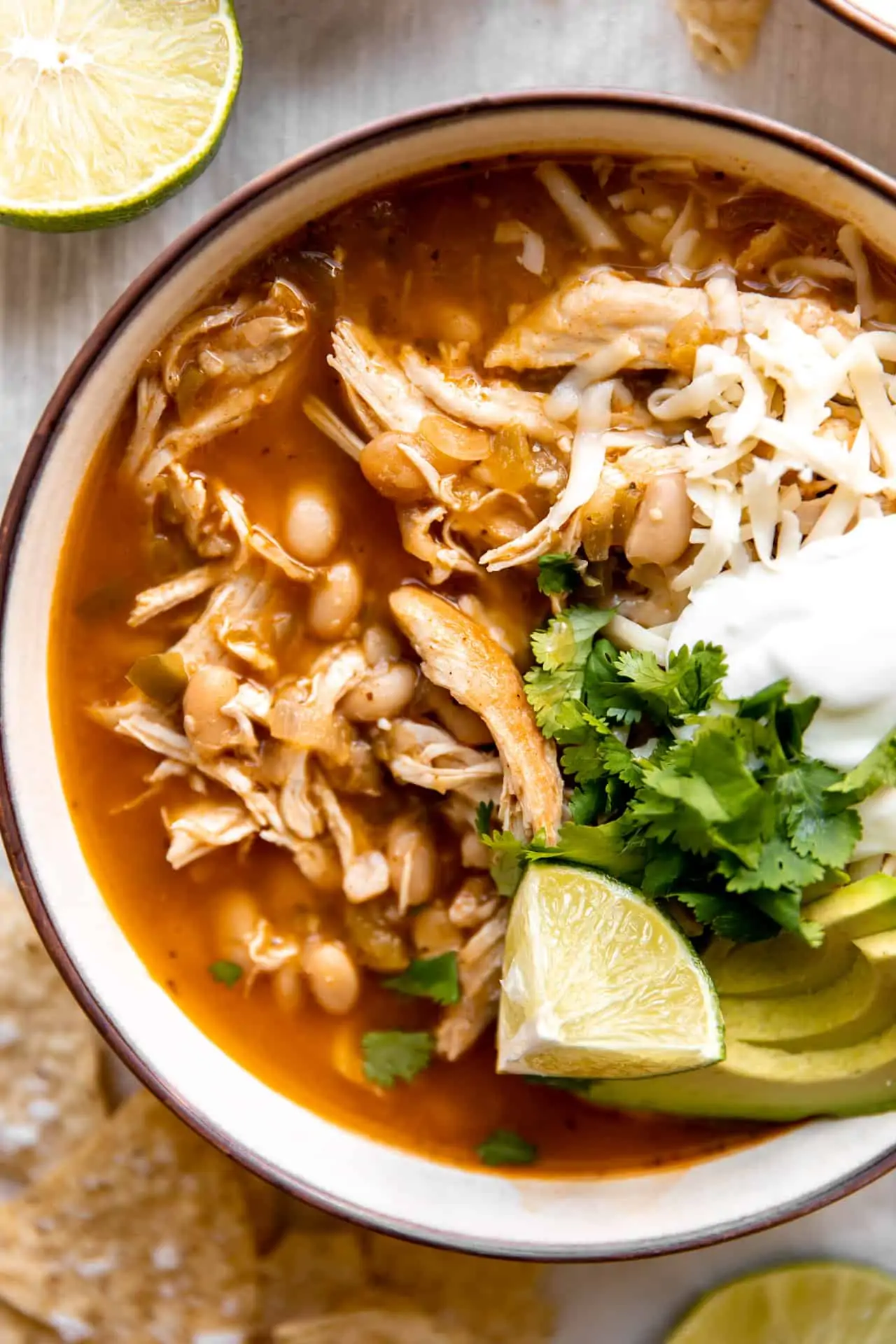Up close view of chicken chili with toppings of sour cream, cheese, cilantro and avocado.