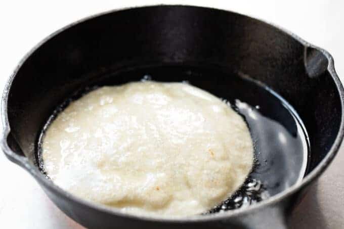 Frying tortillas in oil in a small cast iron skillet. 
