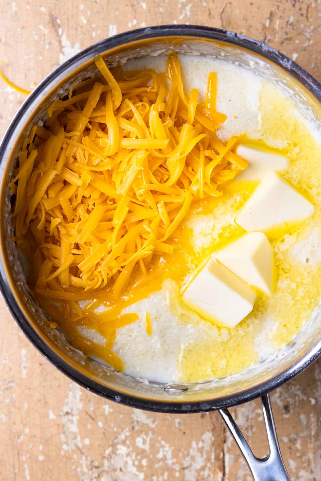 How to make cheese grits, showing adding butter and cheese
