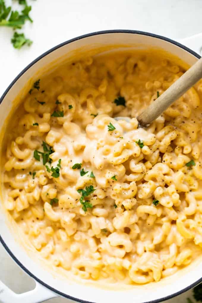 Wooden spoon serving up cheesy macaroni noodles.